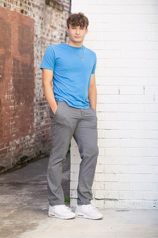 Houston Senior Guy Portrait Downtown Humble wearing Blue Shirt and Gray pants, with trendy white sneakers.