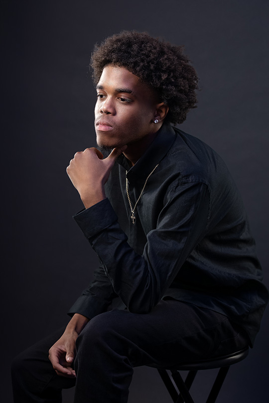 Houston Senior Photographer: Beautiful Magazine Style Senior Portraits By Atascocita Photography 2 Houston Senior guy Studio Portrait. Sophisticated pose in outfit of black shirt and black pants. Moody directional lighting in the studio.